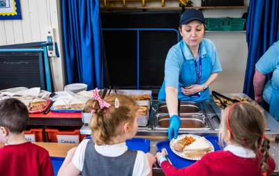 Dinner lady serving meals to primary school children