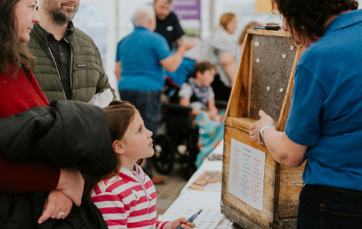 Picture of a woman showing a young girl and and adult male and female a beehive at the Environment Fair in Stockton-on-Tees in 2024