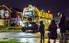 Image of the Santa on Wheels bus as it travels past waving families
