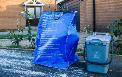 Image of household waste containers on a curbside including blue bag and food caddy