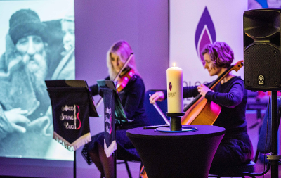Image of remembrance candle and Arco String Duo playing at Holocaust Memorial event